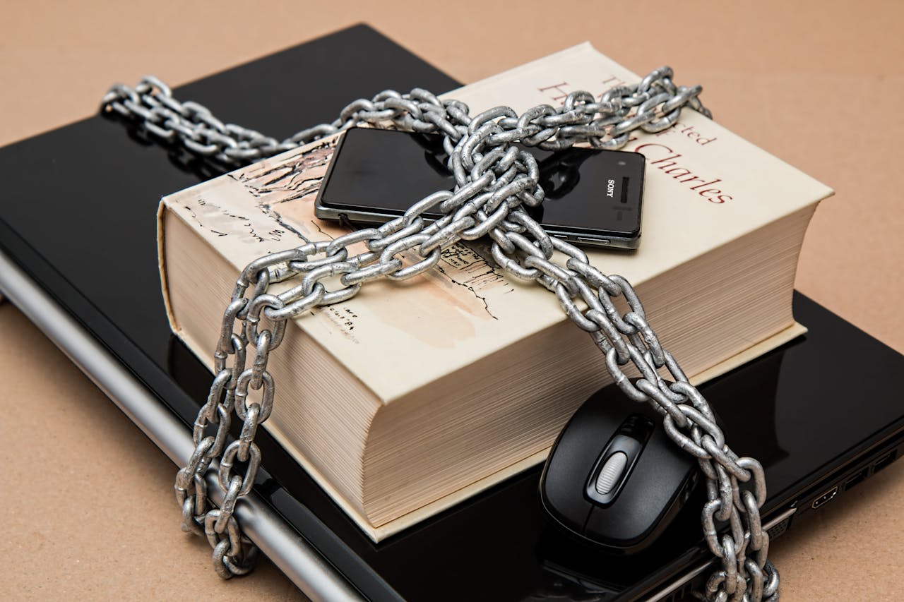 creative-02 Chain-locked book, phone, and laptop symbolizing digital and intellectual security.